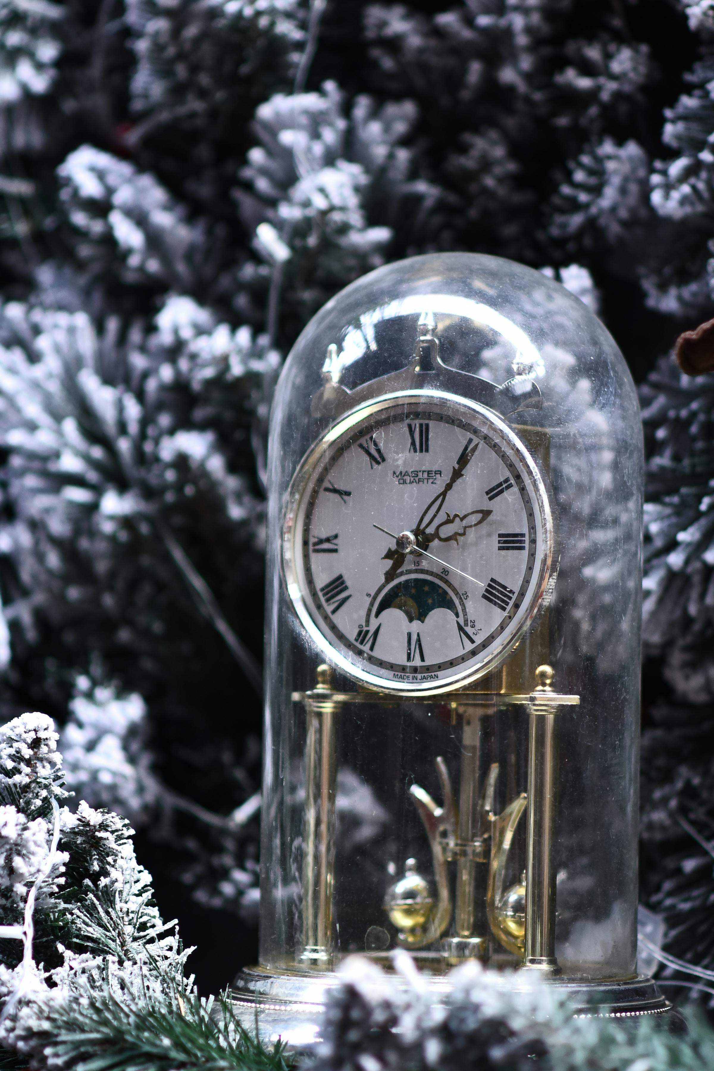 Decorative clock under a glass dome with a snowy background